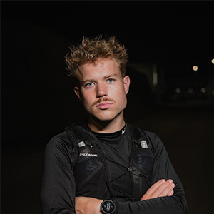 Portret van een man in sportkleding bij nacht, armen gekruist, klaar voor een loop- of outdooractiviteit