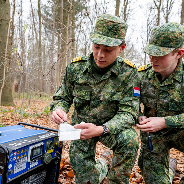 “VeVa-studenten controleren een generator tijdens een technische veldtraining in het bos.”